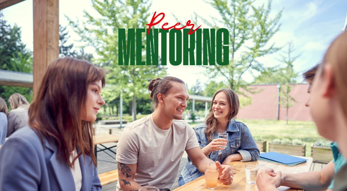 Napis "Peer-mentoring" a w tle grupa studentów siedząca przy stołówce